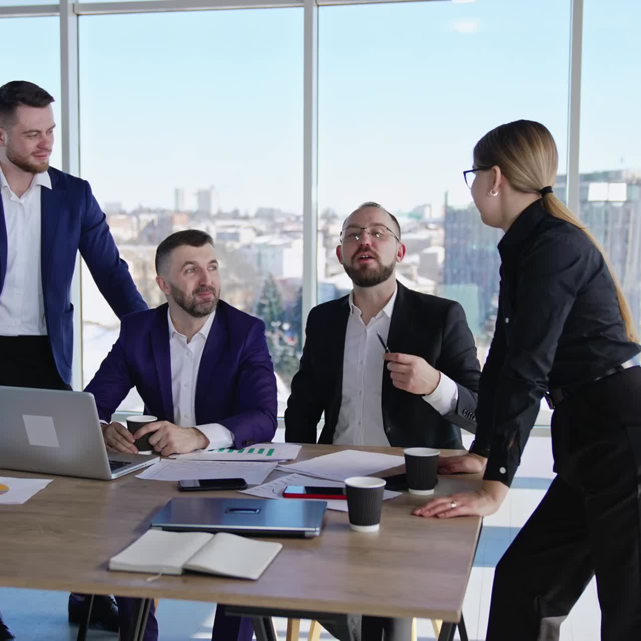 Coworkers having a conversation sitting or standing at the table. Friendly business environment in the office. Colleagues chatting and smiling at work