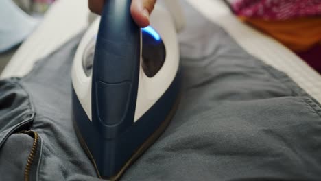 closeup of a woman ironing clothing by stream iron on board at home