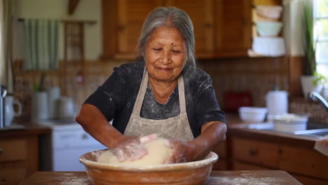 elderly woman kneading dough in a kitchen