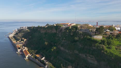 Rising-drone-shot-of-coastal-Almada-town-in-Portugal-at-sunset