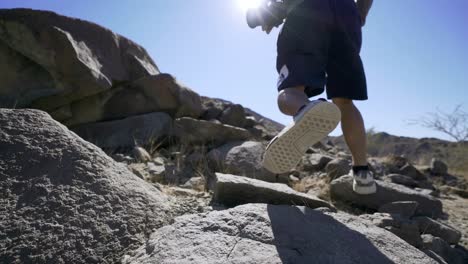 guy vlogger man climbing a rocky mountain with camera in summer sunny day