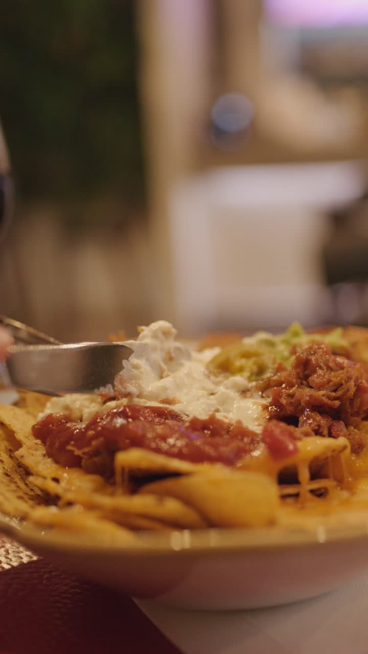 Primo piano di nachos raccolti con salsa, illuminazione ambientale calda, profondità di campo ridotta
