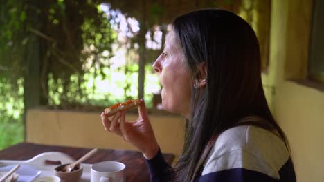 woman enjoying breakfast of toast and homemade peach jam