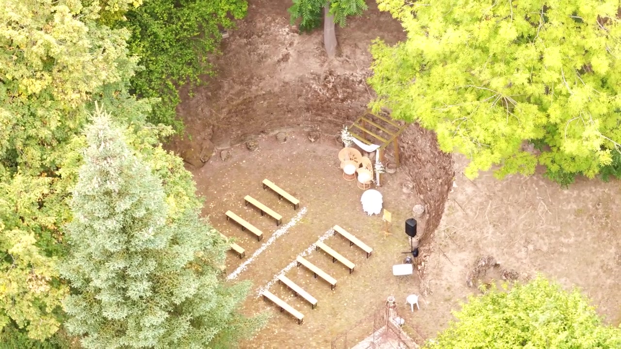 Aerial view shows outdoor ceremony seating arrangement in a woodland clearing