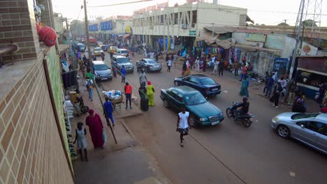 Static shot of a busy street at serekunda market in gambia with view of locals and tourists and busy street with shops on a beautiful morning