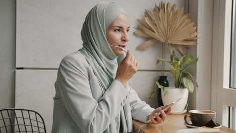 Businesswoman in Hijab on Video Call in a Cafe