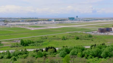 campo de aeropuerto siempre verde de yvr- aeropuerto internacional de vancouver con un avión de aterrizaje en el fondo en richmond, columbia británica, canadá