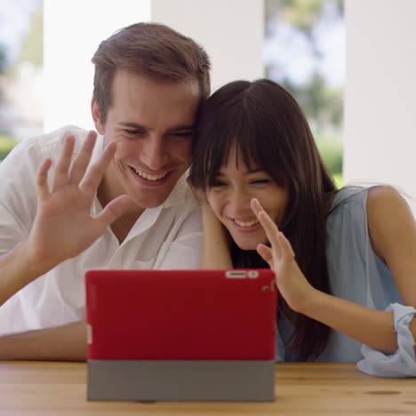 Man-and-woman-waving-at-their-tablet-computer