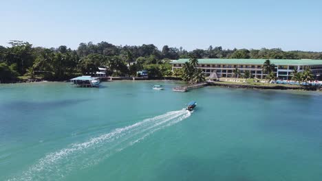 aerial: tourism tour boat returns to hotel beach resort dock, panama