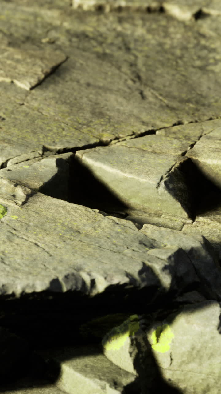 Rocce con licheni verdi illuminate dal sole in un sito naturale durante il giorno.