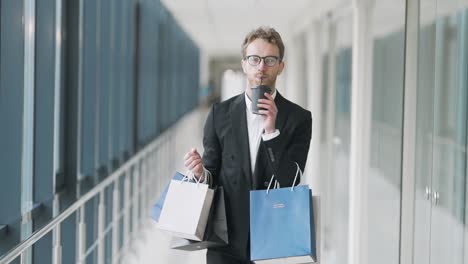 Stylish-man-with-coffee-walking-down-the-hall-receives-a-joyful-notification