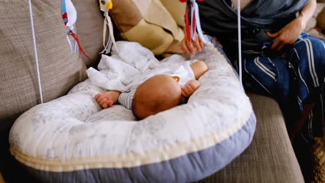 young woman putting her baby in crib to sleep on sofa 4k