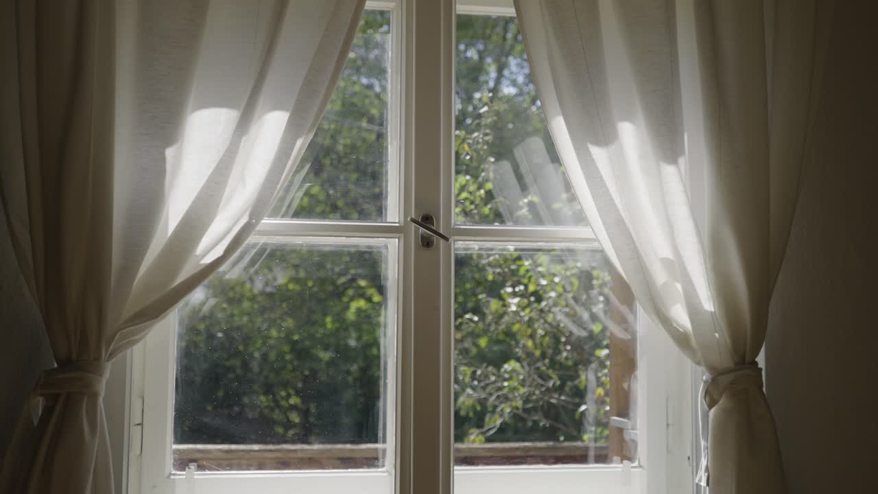 Soft morning light shining through white curtains inside a cozy room. Calm minimal interior atmosphere with natural glow