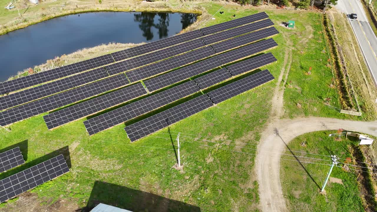 Drone footage captures expansive solar panels on a sunny day, highlighting renewable energy efforts in a rural New Zealand setting