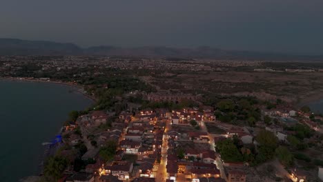 Turkey,-Side-old-town-illuminated-coastal-homes-aerial-view-flying-over-buildings-rooftops-at-sunset