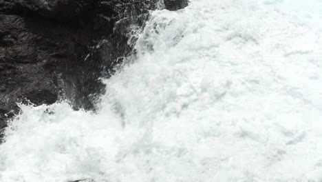 Close-up-of-big-waves-crashing-into-black-lava-rocks,-power-of-nature