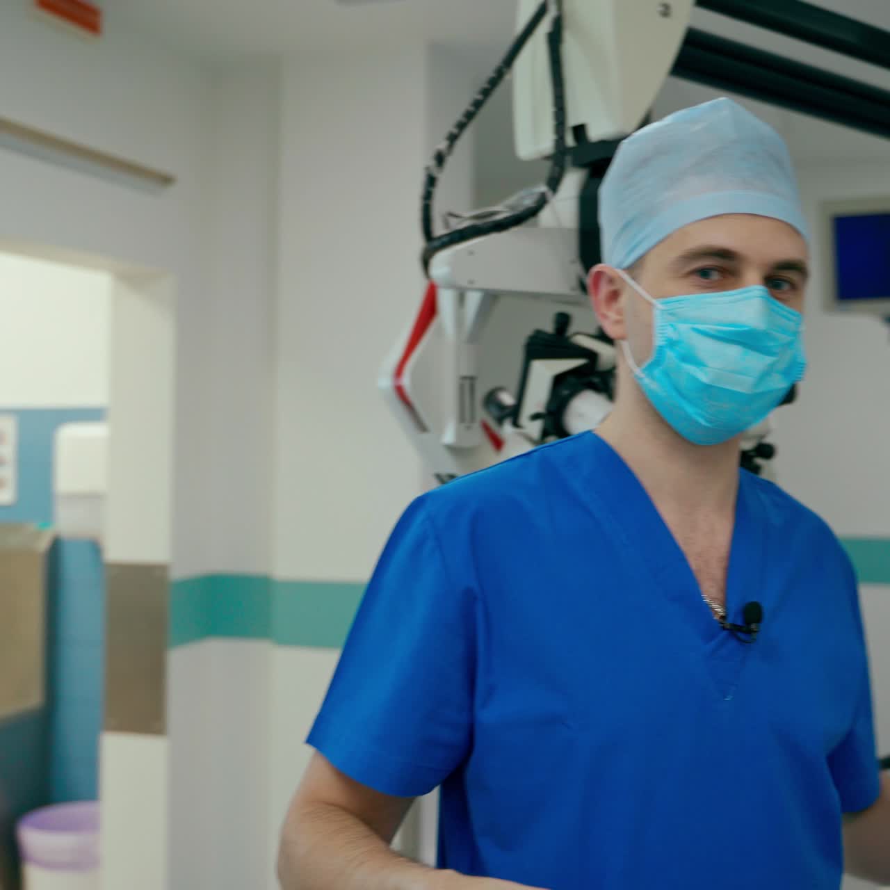 Surgeon comes to the operating room in hospital. Professional doctor in blue medical uniform and mask before the surgery in the modern operating theater.