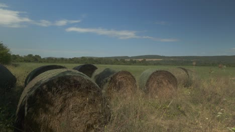 Bales-of-hay-in-corner-of-farmland-crop-field-in-summer-countryside-scene