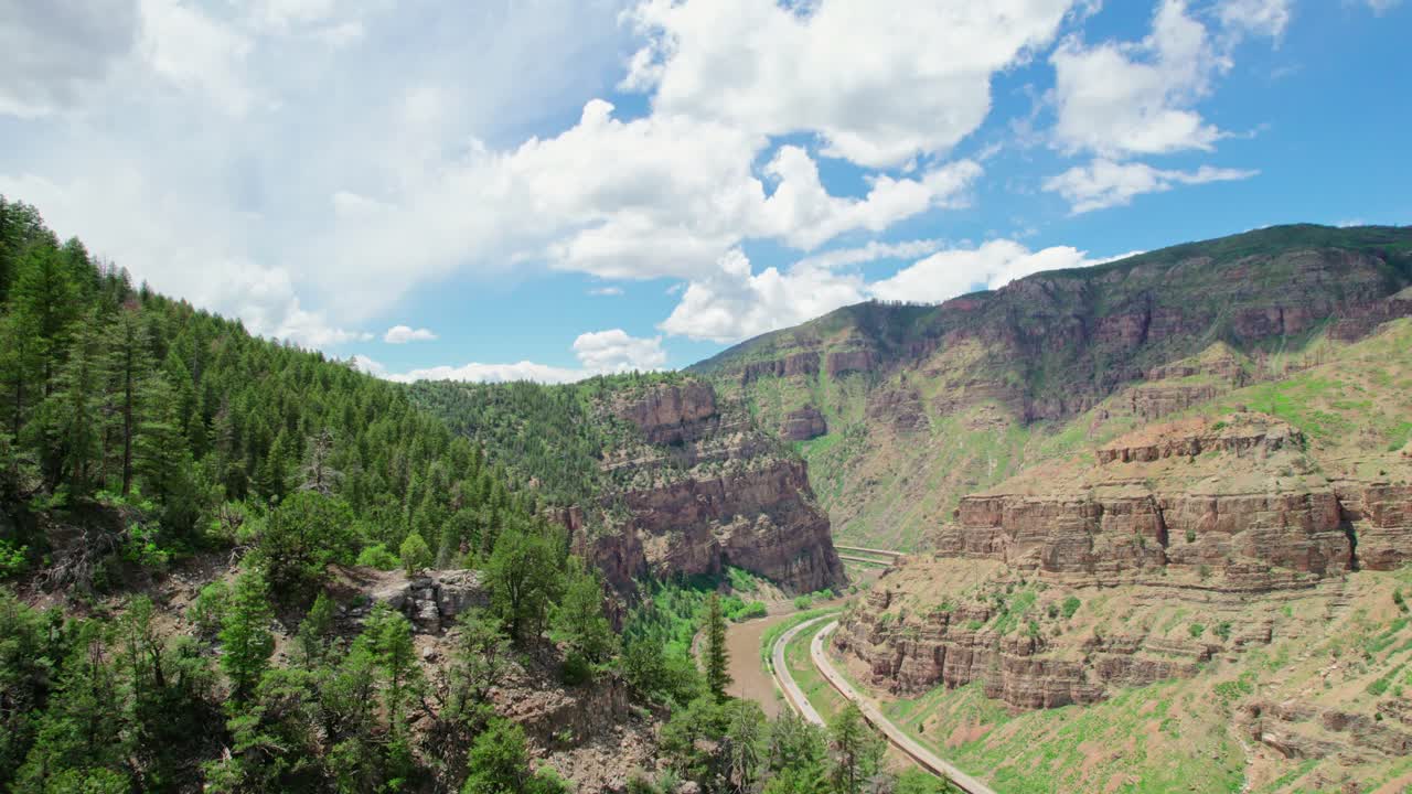 글렌우드 캐년 콜로라도 미국에서 따뜻한 더운 여름날 동안 건강한 녹색 고산 나무와 서사시 아름다운 광활한 협곡을 드러내는 나무로 덮인 바위 협곡 절벽 위로 날아갑니다.