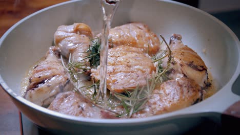 pouring wine into a pan fried chicken dish in a skillet