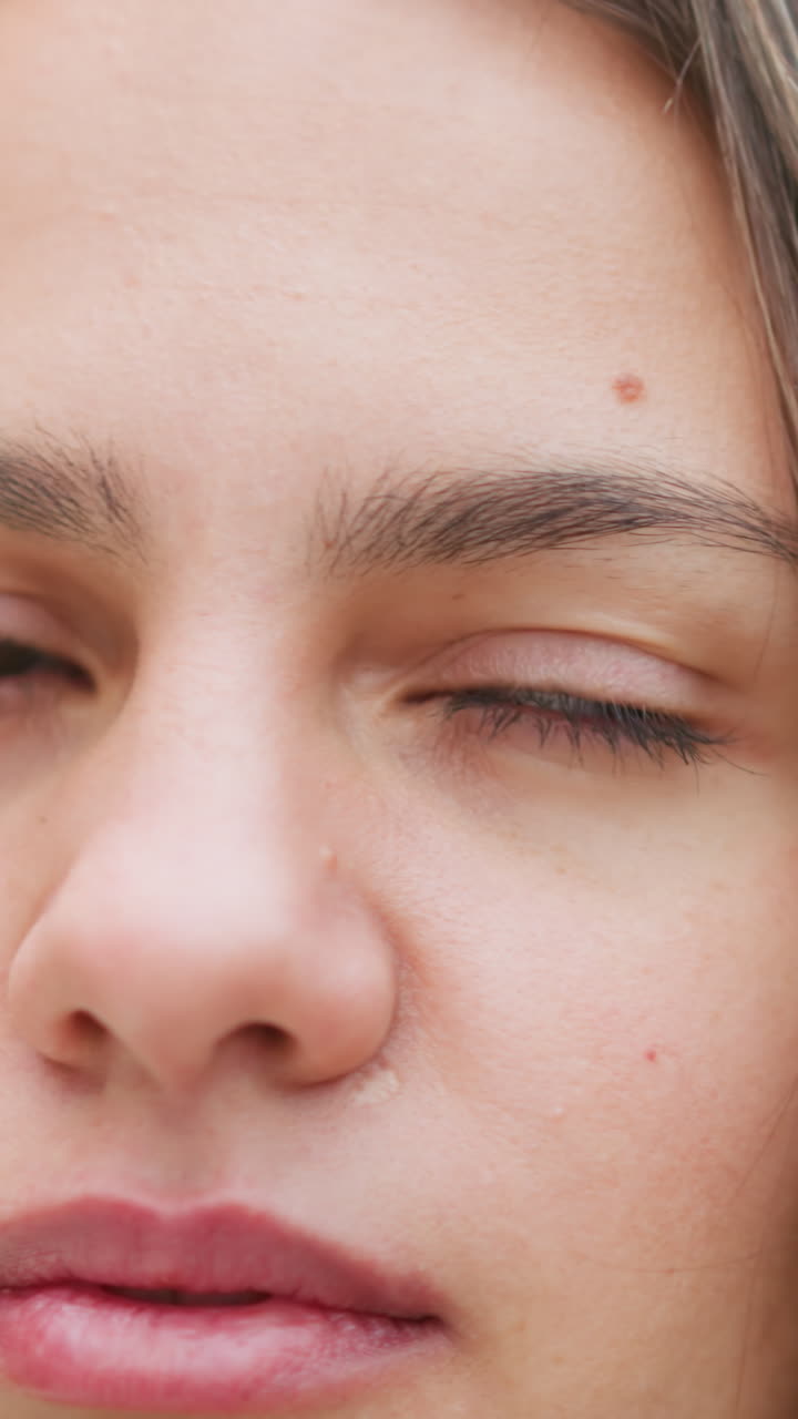 Close-up portrait view of woman blinking eyes, focused expression, natural look, casual outdoor shot, calm mood, soft gaze, beauty shot, personal moment, calmness, serenity
