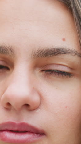 close-up portretbeeld van een vrouw met knipperende ogen, gefocuste uitdrukking, natuurlijke uitstraling, casual buitenopname, rustige stemming, zachte blik, schoonheidsopname, persoonlijk moment, kalmte, sereniteit