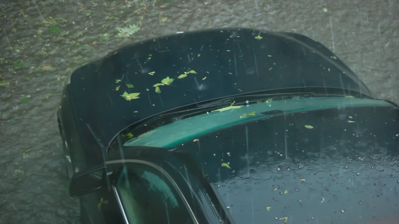 뷰는 검은 차 앞을 보여줍니다. 강한 비와 우박 폭풍에 빠져 있습니다.