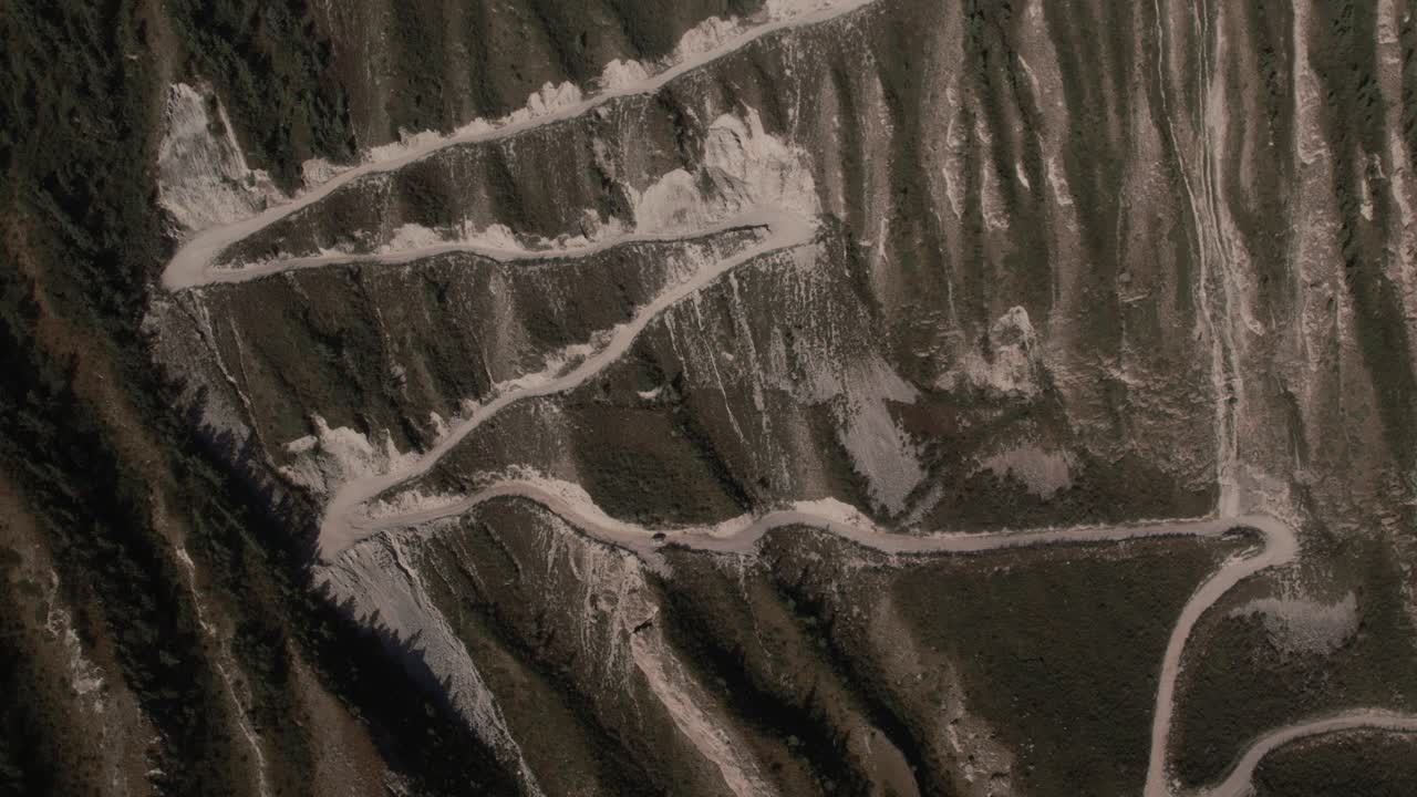 Top down aerial footage of the winding gravel road with sharp switchbacks on Katu-Yaryk Pass above Chulyshman Valley, Altai Republic, Russia
