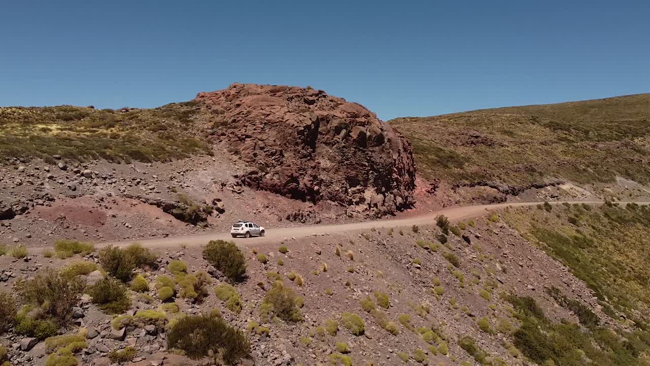 남미 아르헨티나 파타고니아 산맥의 자연 경관을 통해 자동차가 도로에서 천천히 움직이고 있습니다.