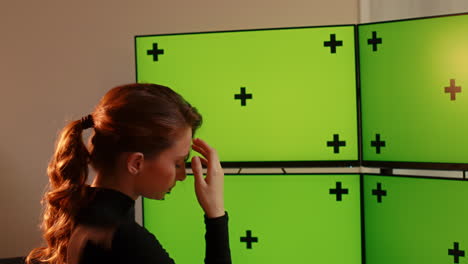 young woman, disappointed, multiple green screen computer monitors with tracking