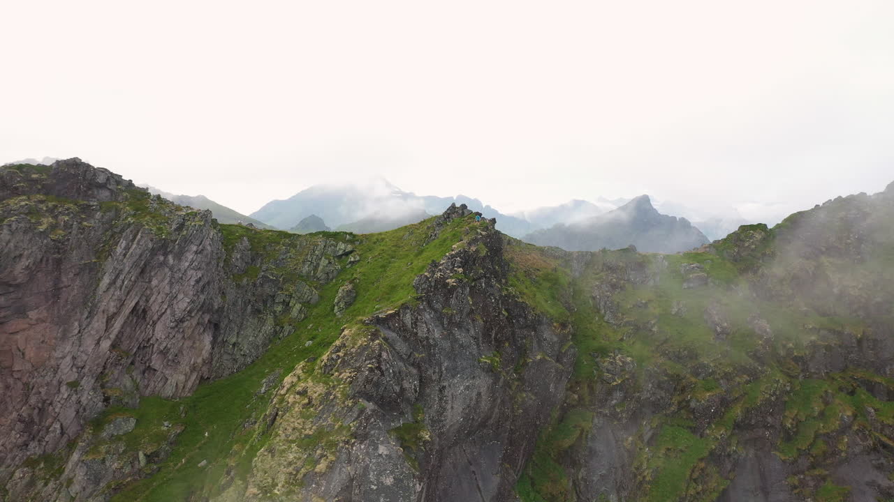 Rotating drone shot mountain ridge moving through the clouds, Fl&oslash;ya and Djevelporten above Svolv&aelig;r in Lofoten, Norway, aerial footage