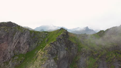 rotating drone shot mountain ridge moving through the clouds, fløya and djevelporten above svolvær in lofoten, norway, aerial footage