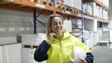 trabajadora sonriente quitándose el casco y mirando la cámara