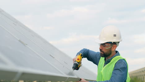 hombre caucásico con uniforme especial y casco protector reparando un panel solar