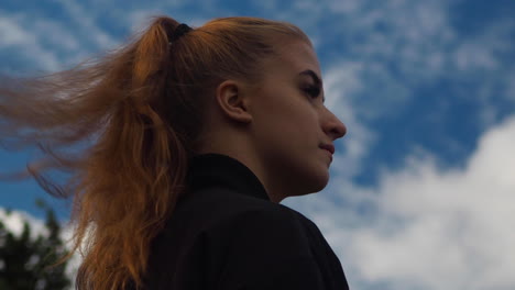 close shot of young girl staring at the view and wind blows her long hair