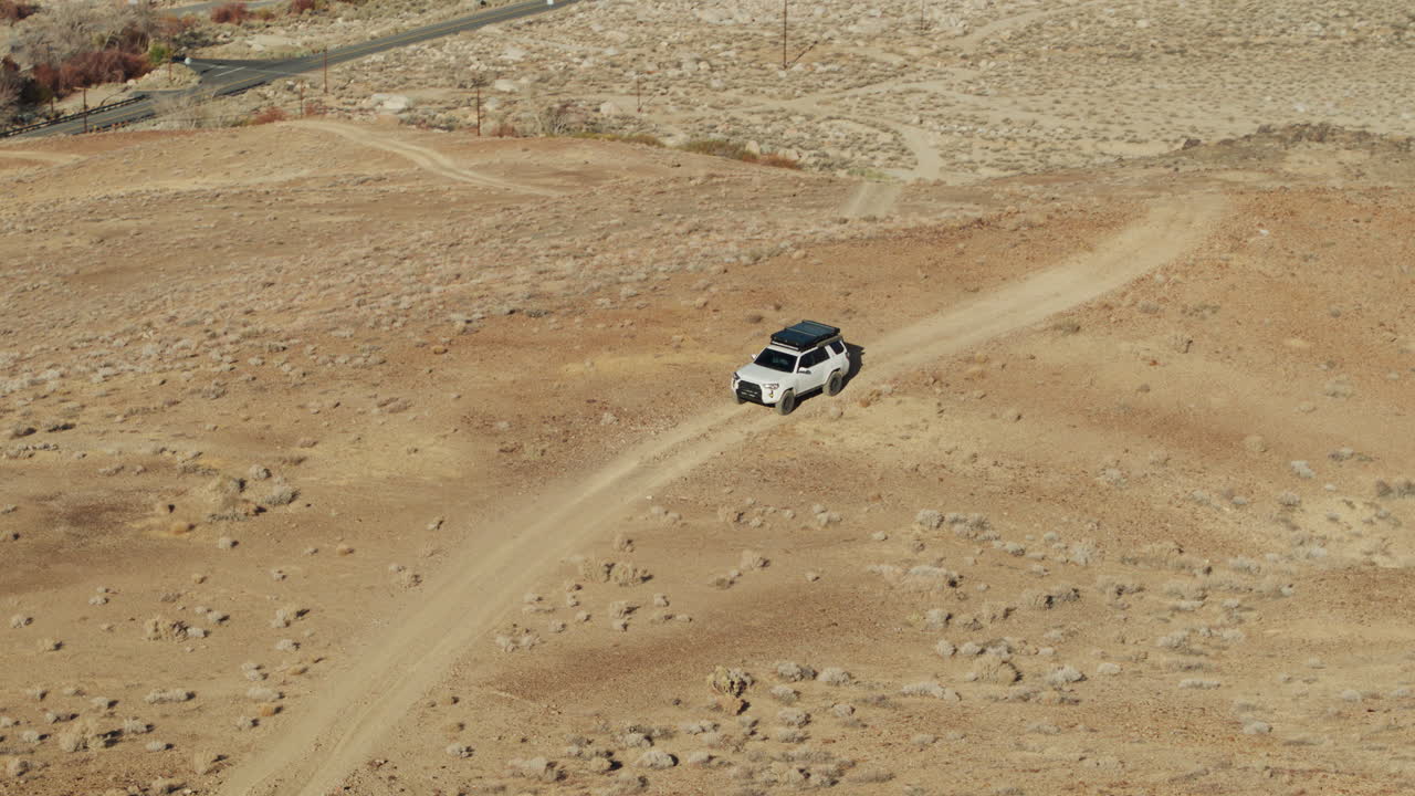 SUV 4x4 bianco che guida su una strada sterrata attraverso le Alabama Hills, vista aerea