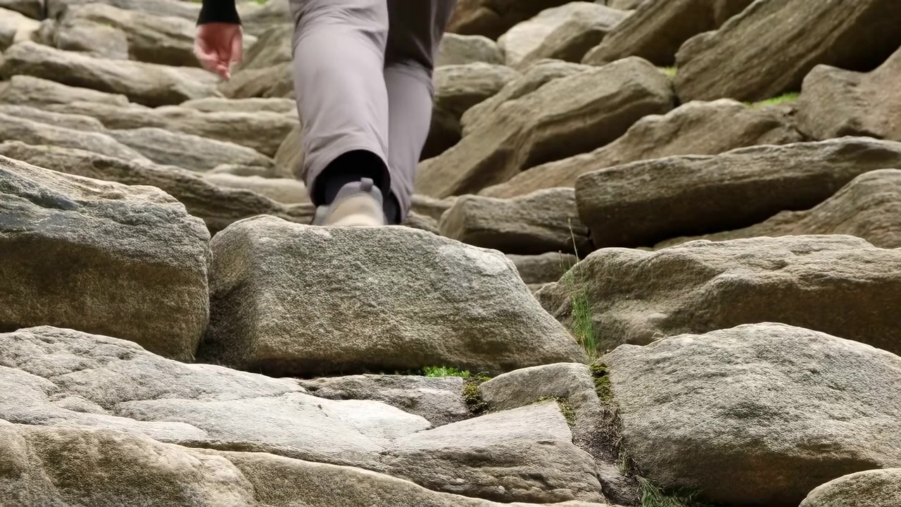 Close-up de Bota de Caminhada Subindo em Degraus Rochosos, Ascensão ao Ar Livre Capturada de Ângulo Baixo, Pernas Vestidas com Calças