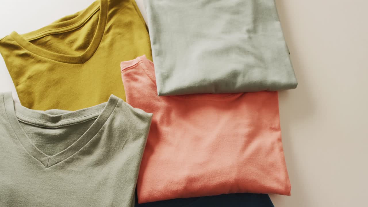 Video of close up of folded t shirts on white background
