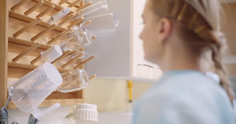 Toma-De-Mano-De-Mujer-Científico-Manteniendo-Vaso-De-Vidrio-En-Estante-De-Madera-En-Laboratorio