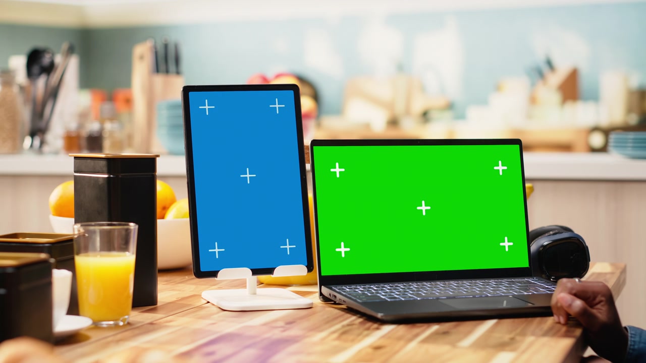 Schermo blu verticale e chroma key su tablet e laptop vicino a una lavoratrice.