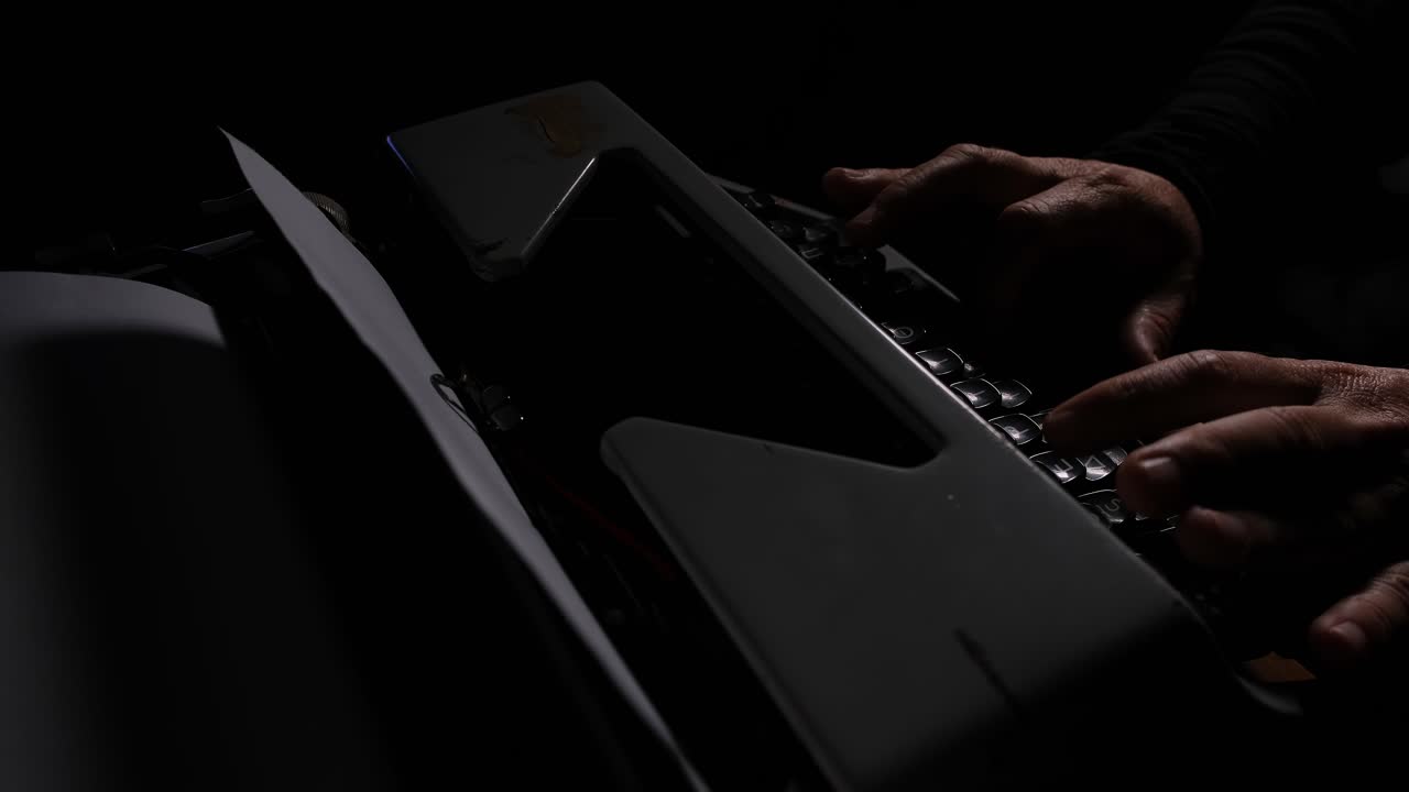 Mysterious shot of hands typing on a vintage typewriter in the dark