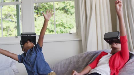 Diversos-Niños-Y-Niñas-Sentados-En-Casa-En-Un-Sofá-Jugando-Con-Gafas-De-Realidad-Virtual