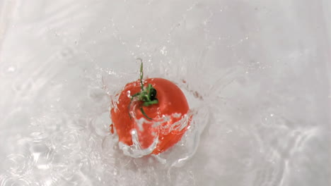 tomato falling into water in super slow motion