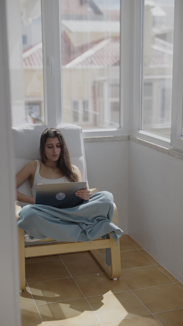 Donna che lavora al portatile sul balcone