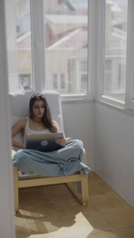mujer trabajando en una computadora portátil en el balcón