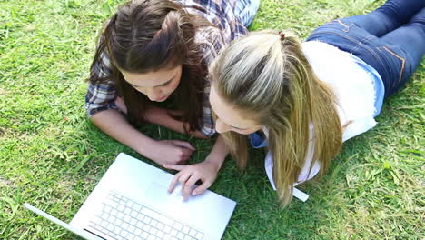 friends lying together while using a laptop