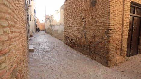 warm sunset light bathes an old muslim street with brick buildings in sbeitla, wooden door in view