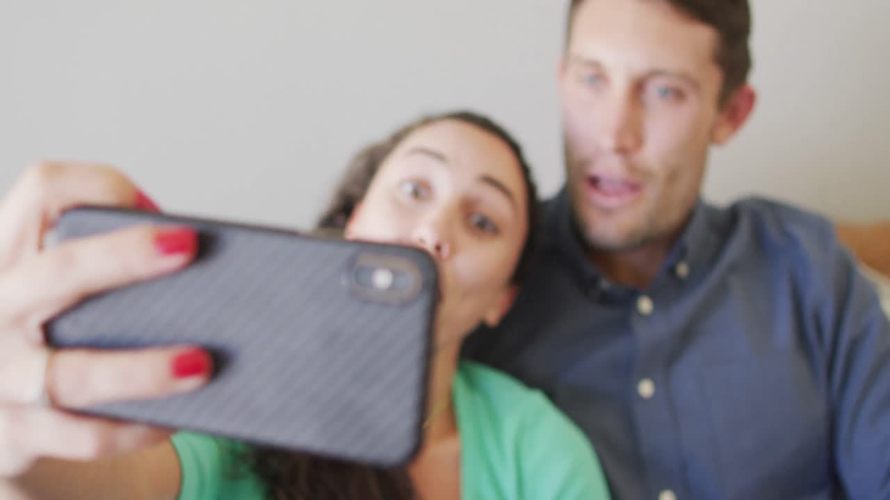 una joven pareja caucásica feliz enamorada sonriendo y tomándose una selfie