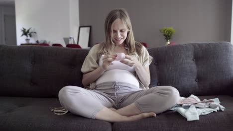 happy pregnant woman looking at clothing for child