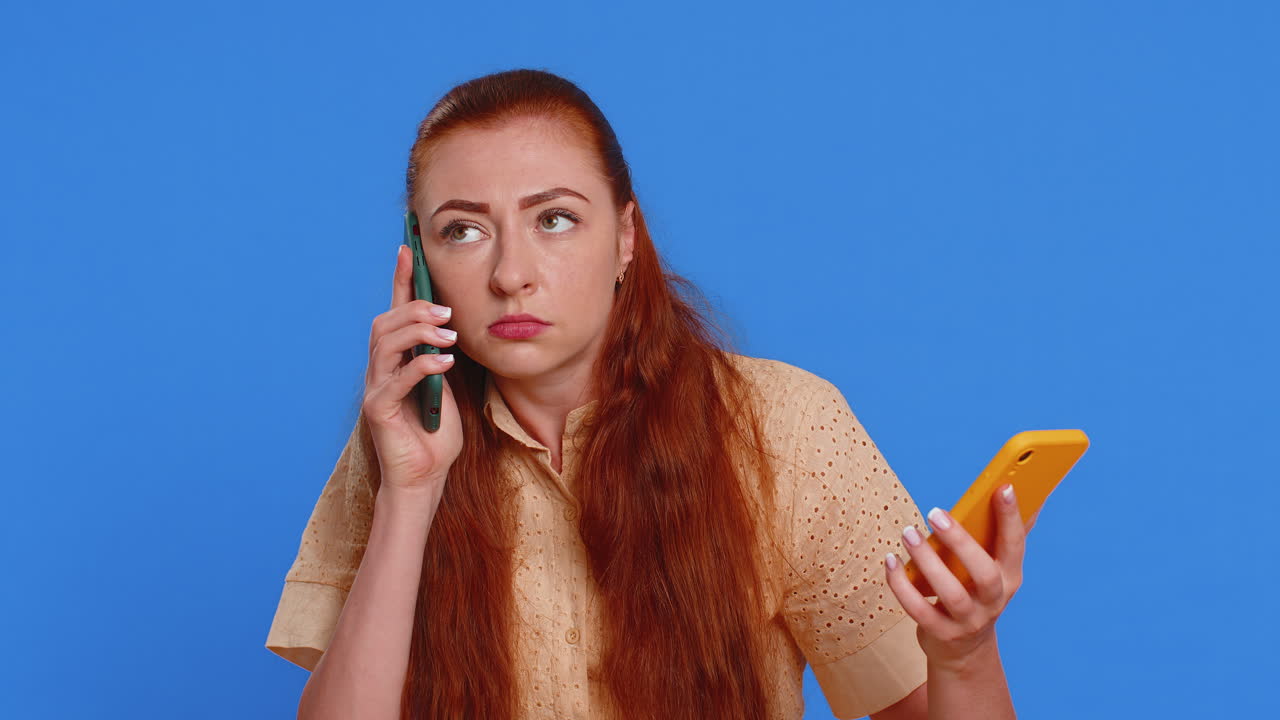 irritada estresada mujer de negocios hablando en dos teléfonos móviles teniendo conversación conflicto pelea